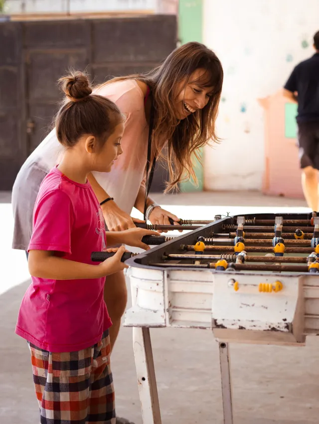 Una educadora acompaña a una niña en una actividad.